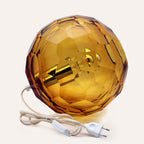 Medium amber spherical Murano glass table lamp with a hand-sculpted faceted surface, handcrafted on Murano Island in Venice, Italy.